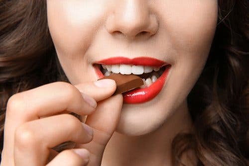 Femme qui mange un carré de chocolat.