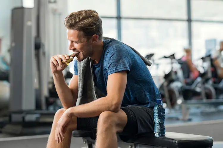 Hombre comiendo barrita gimnasio