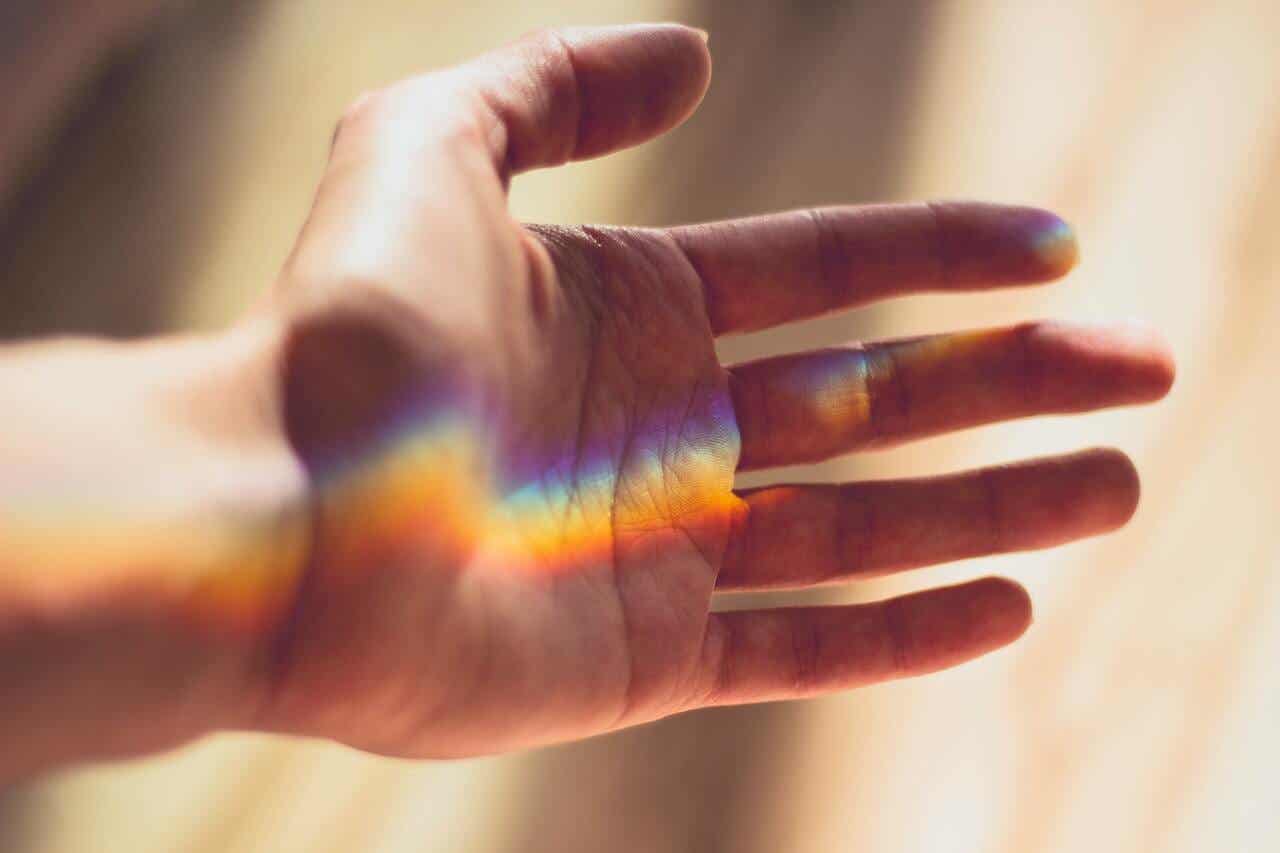 Farbpsychologie - Hand mit Reflexion von Regenbogenfarben