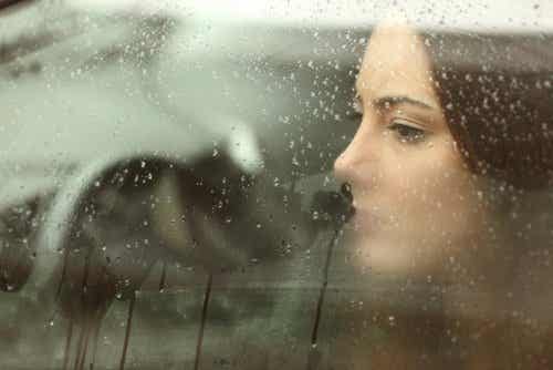 Mujer aceptando ruptura de pareja mirando por una ventana