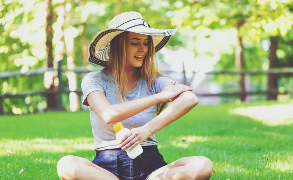 Mujer aplicándose crema solar.