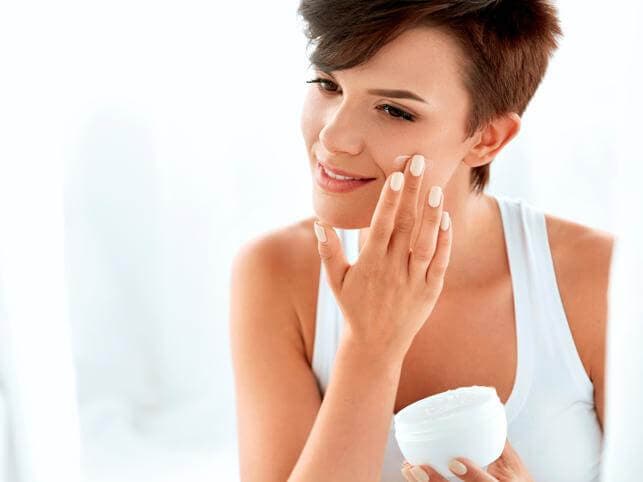 Chica aplicándose una crema.