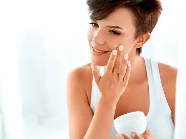 Chica aplicándose una crema.