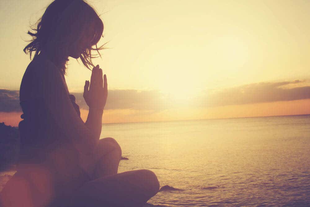 Mujer meditando al amanecer.