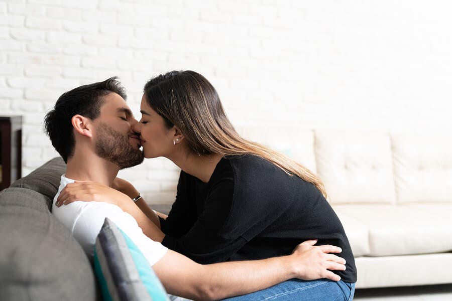 Pareja besándose en el sofá.