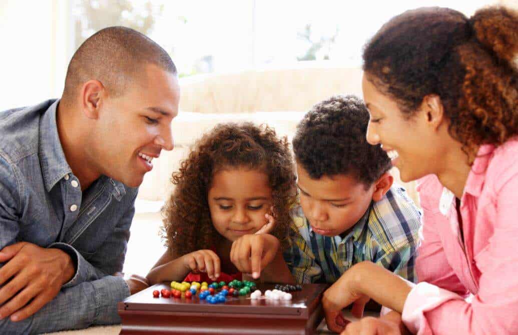 Familia divirtiéndose con juegos de mesa, una buena opción para aprender a trabajar en equipo.