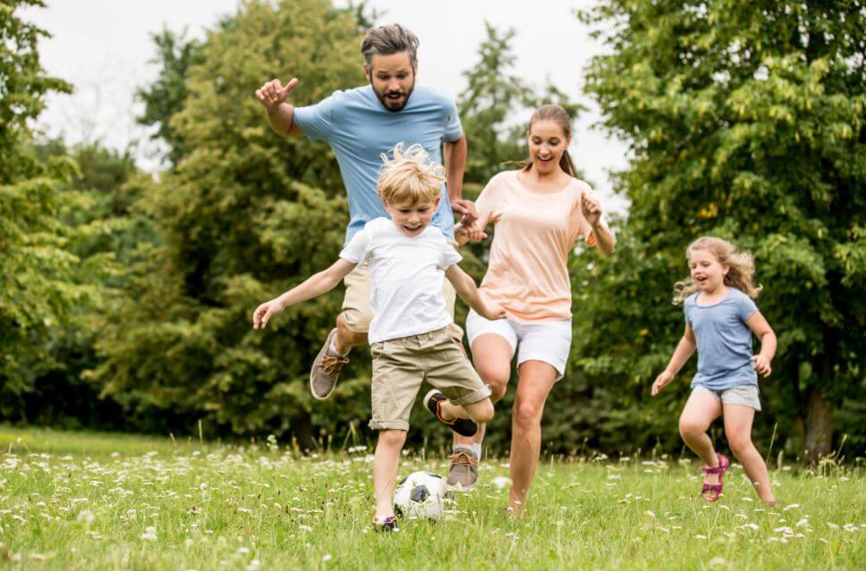 Padre y sus tres hijos jugando con el balón en el jardín de su casa