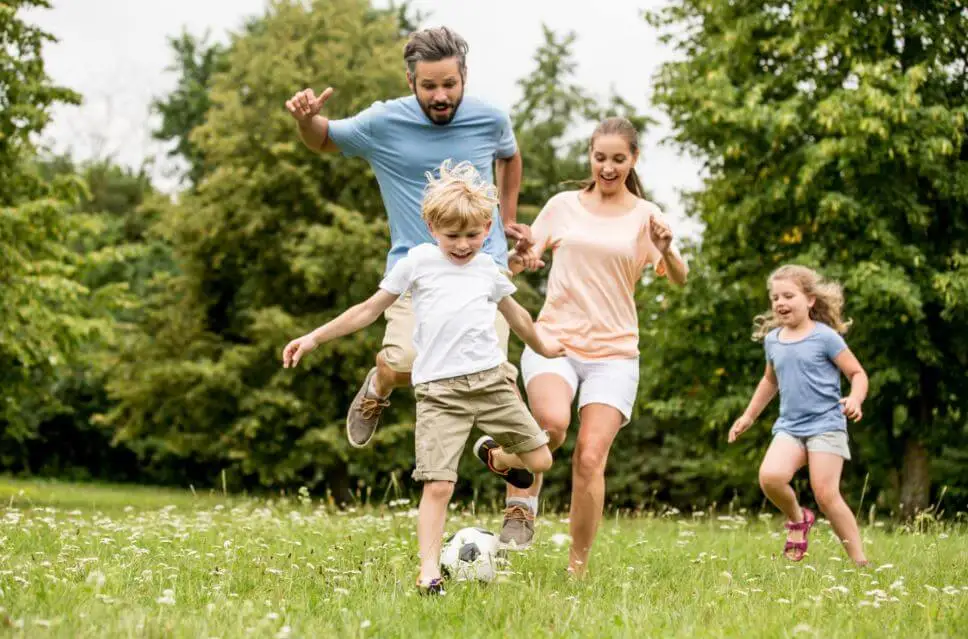 Padre y sus tres hijos jugando con el balón en el jardín de su casa