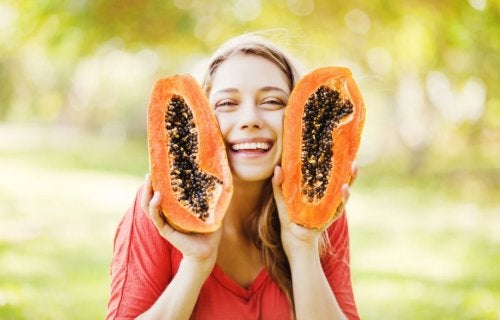mujer sosteniendo dos mitades de papaya