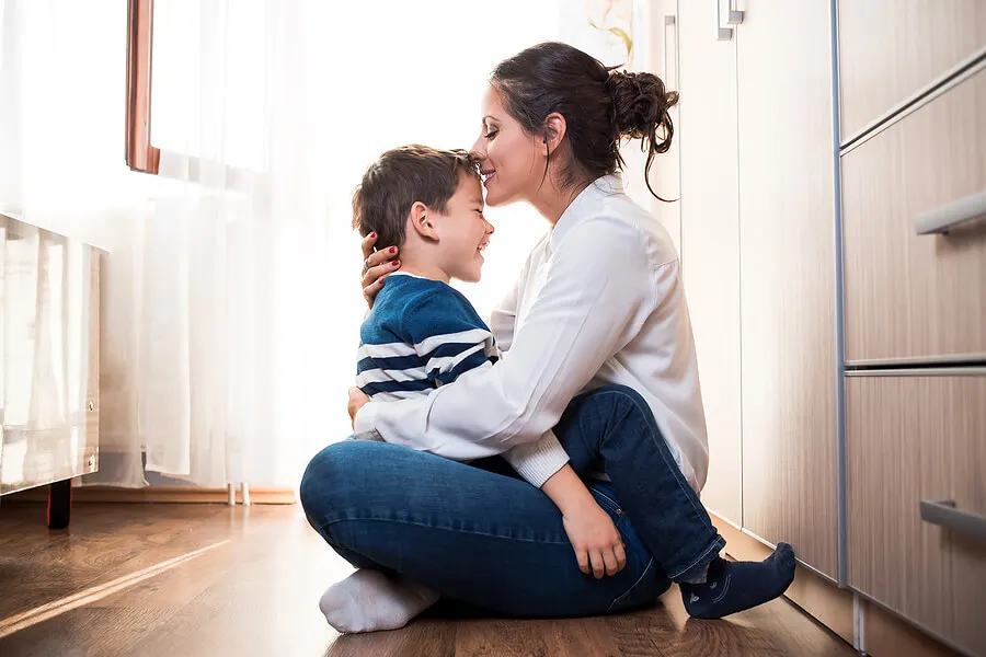 Madre dándole un beso en la frente a su hijo