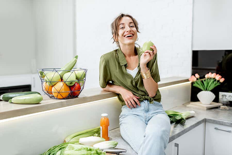 Женщина на кухне с овощами вокруг.