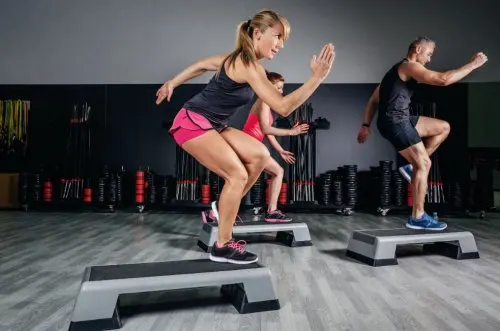 Personas en el gimnasio haciendo ejercicio aeróbico.