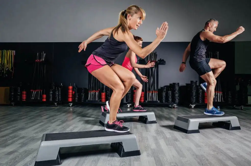 Les gens dans la salle de gym font de l'exercice aérobique.