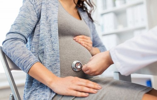 Tripa de embarazada siendo auscultada por un médico.