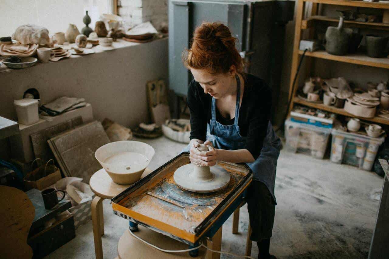 La femme fabrique des objets à partir d'argile et de boue.