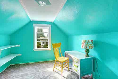 Habitación con paredes de un azul vibrante con un escritorio, una lámpara y una silla amarila