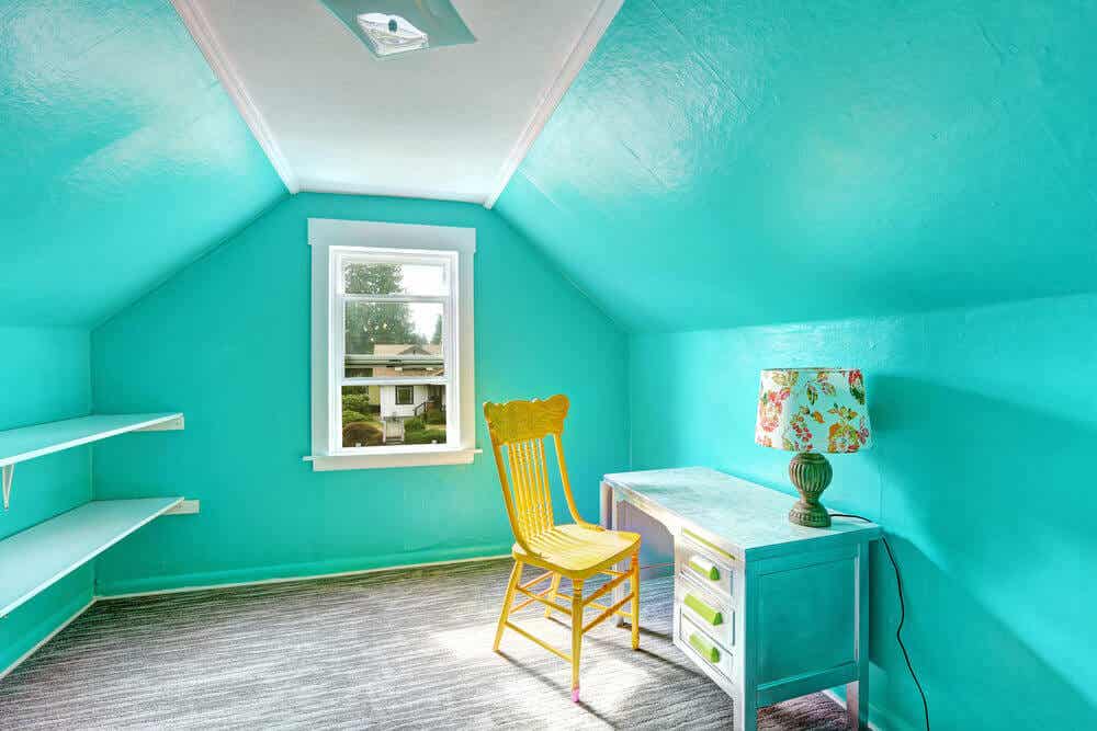 Habitación con paredes de un azul vibrante con un escritorio, una lámpara y una silla amarila.