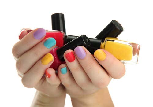 Manos con las uñas pintadas cogiendo esmaltes de colores.