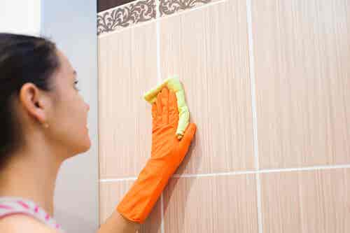 Mujer limpiando los azulejos.