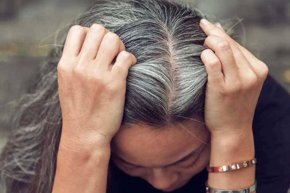 Mujer mostrando raíces canosas.