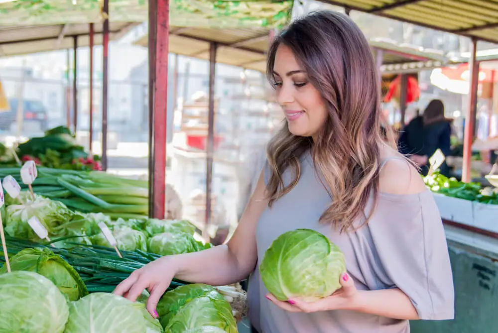 Mujer compra repollo en el mercado.