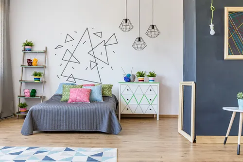Habitación con un mural infantil en la pared a base de triángulos de distintos tamaños y en diferentes orientaciones