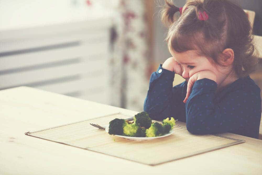 Niña con neofobia alimentaria delante de un plato de brócoli 