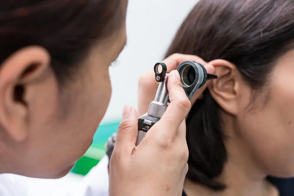 Médico revisa oído tapado por cerumen.