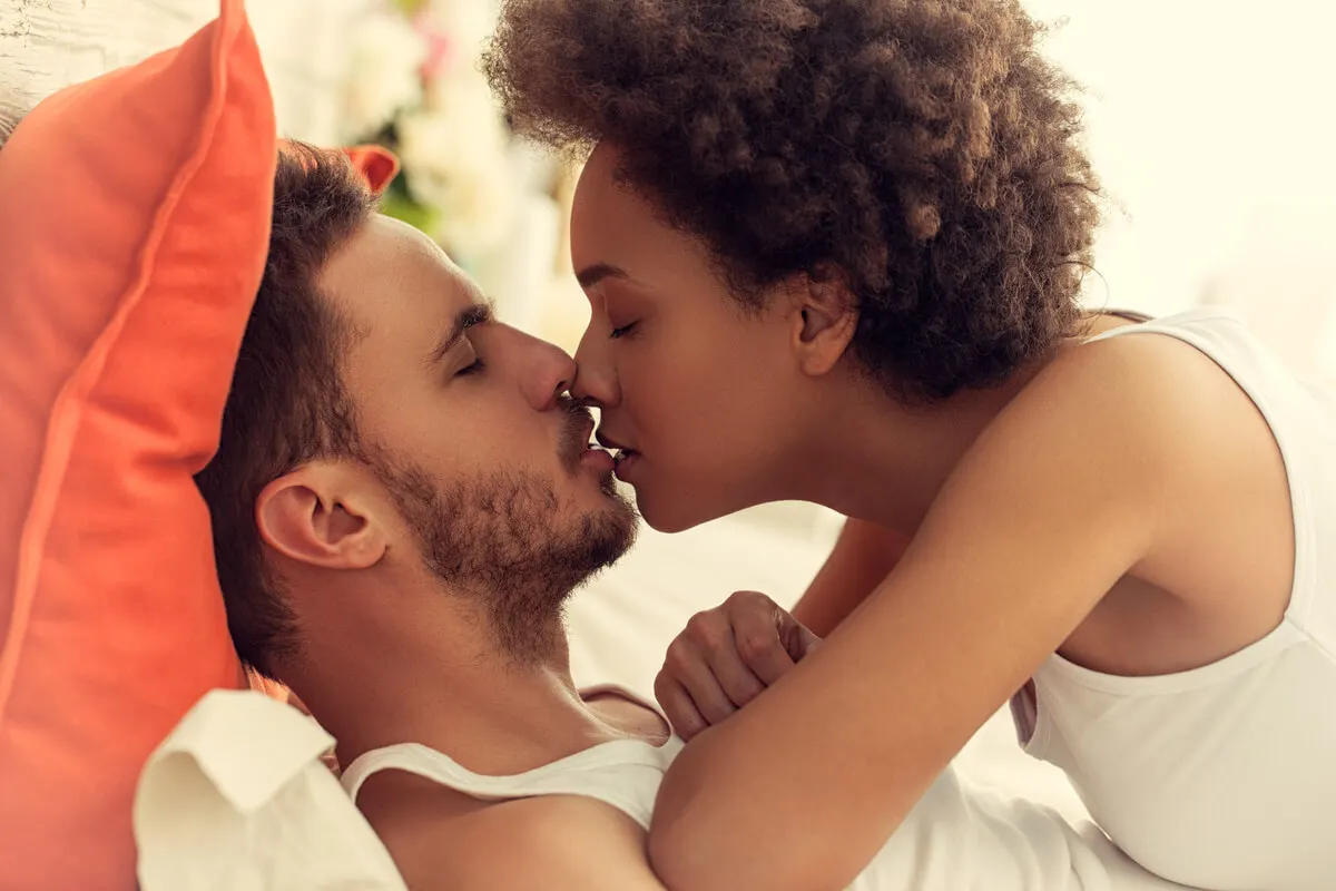 Couple s'embrassant au lit.