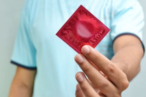 Hombre sujetando un preservativo: prevención del chancroide