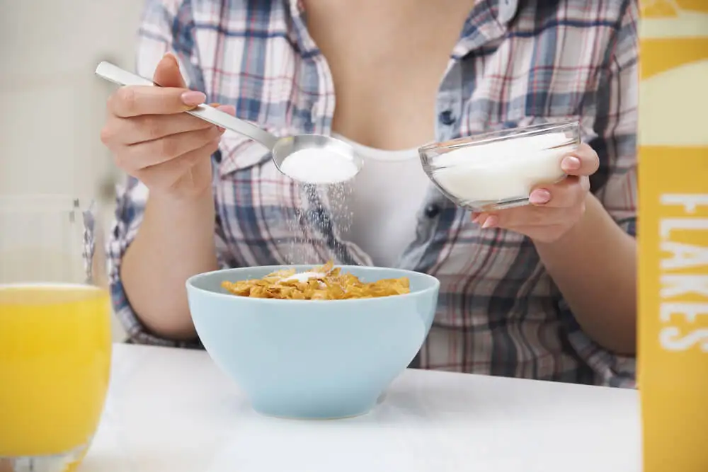 Mujer tomando un bol de cereales con azúcar.