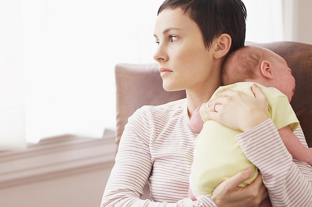 Mujer con depresión posparto con su bebé en brazos.