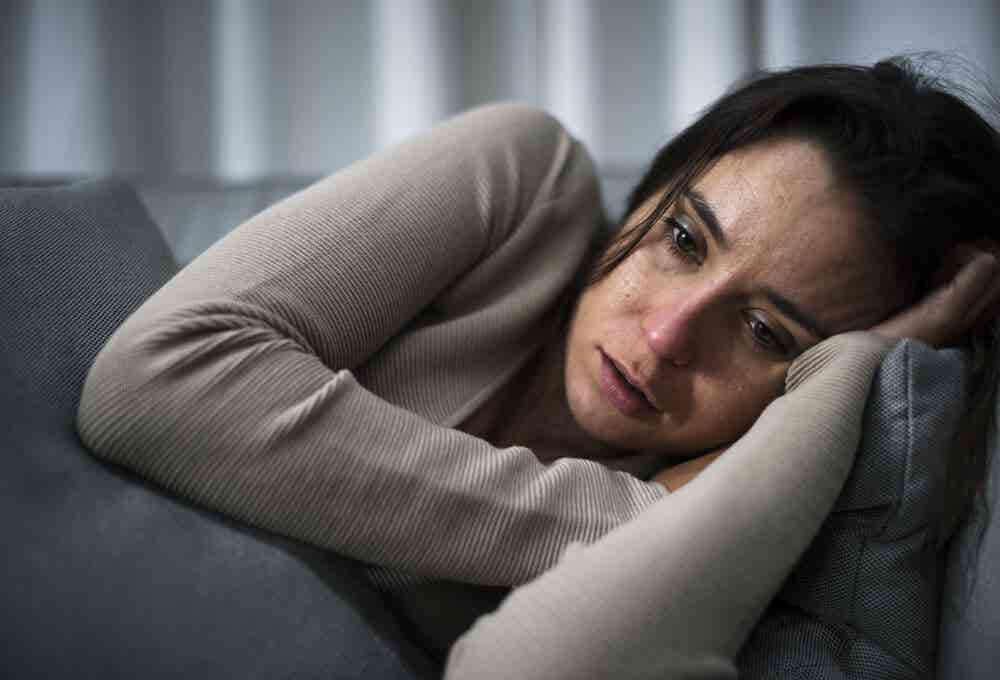 Mujer triste tumbada. Mayor riesgo de suicidio en pacientes con epilepsia.