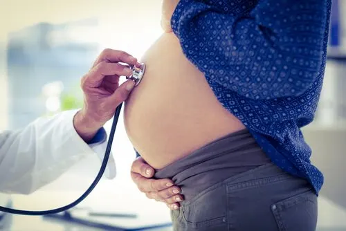 Médico auscultando la tripa de una embarazada