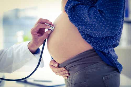 Médico auscultando el abdomen de una embarazada: nacimiento prematuro