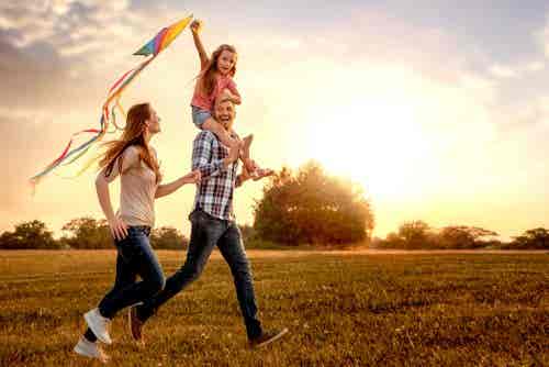 Familia contenta por el campo con una cometa