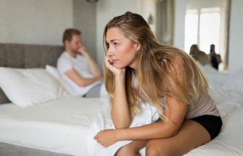 Pareja en la cama con expresión de preocupación