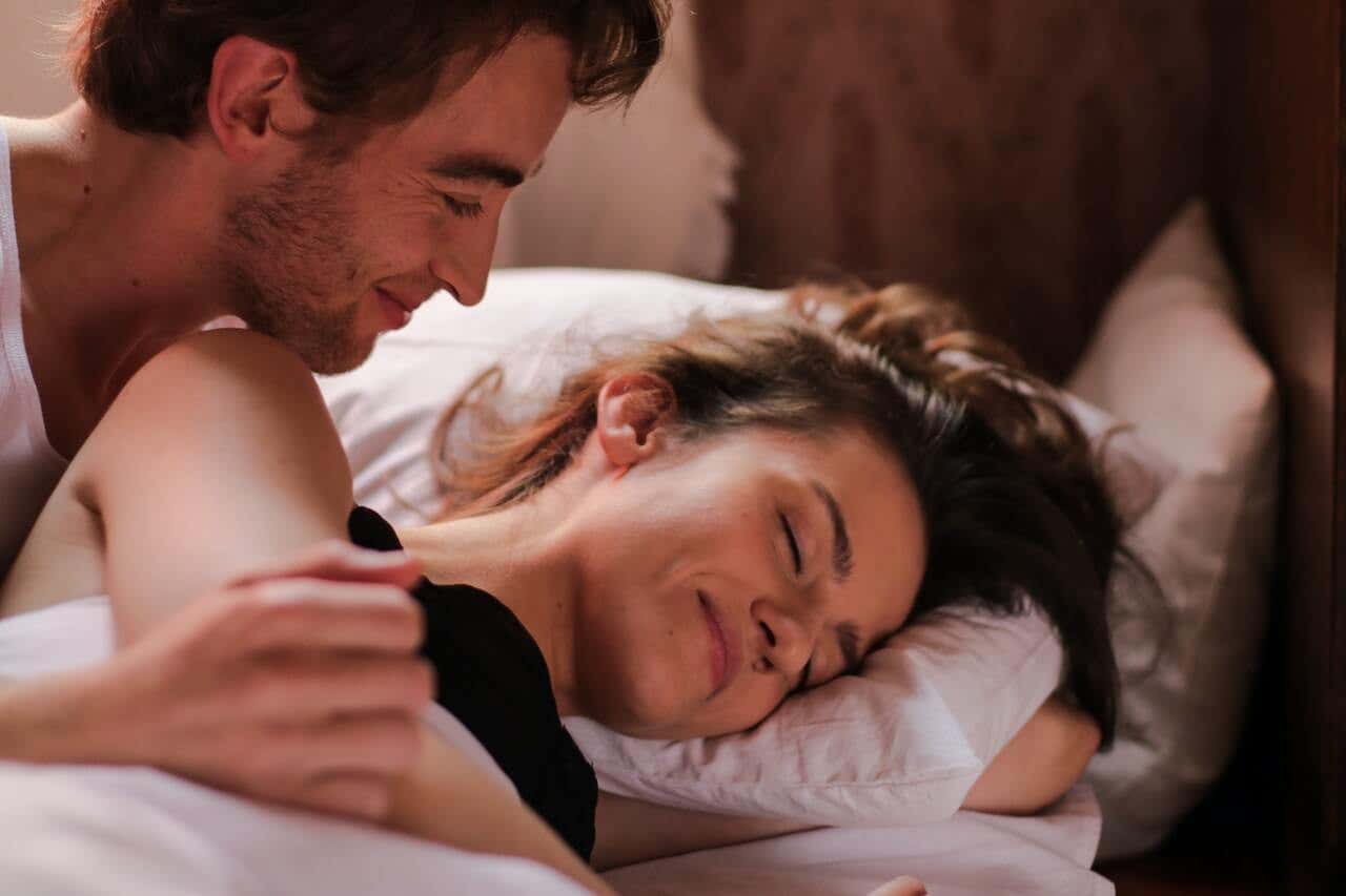 Pareja en la cama teniendo sexo sin penetración.