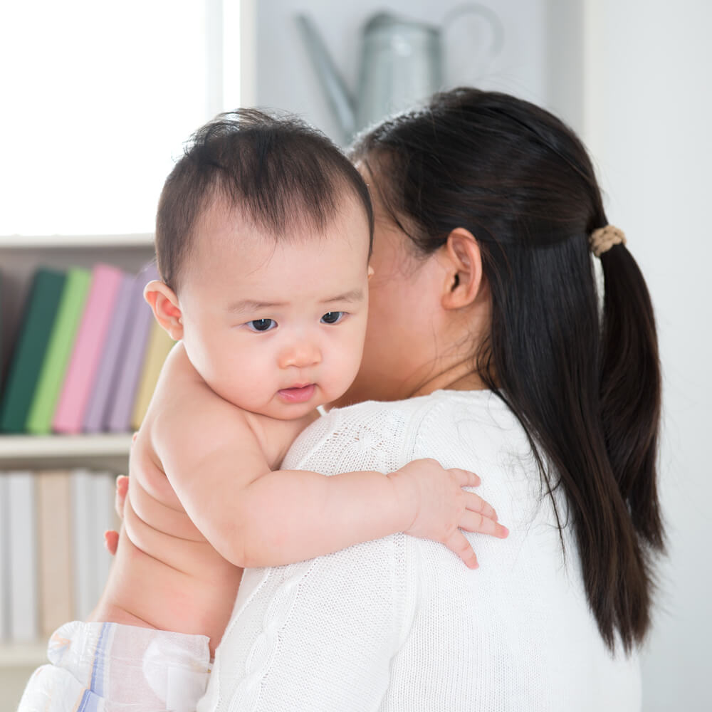 Madre asiática con bebé en brazos.