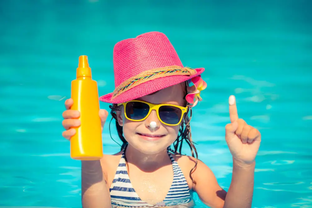 Niña con protector solar en piscina.