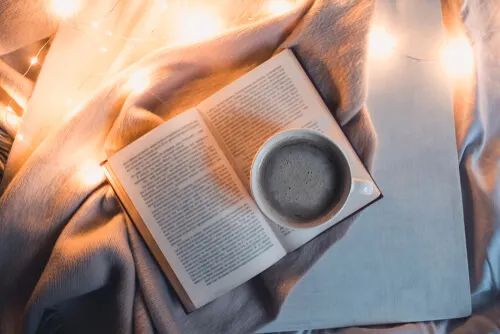 Libro con taza de té en la cama