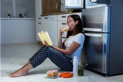 Mujer comiendo en el suelo de la cocina