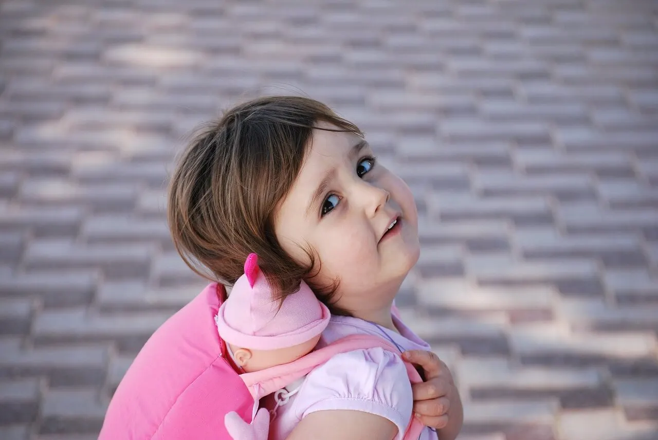 Niña con juguete a la espalda.