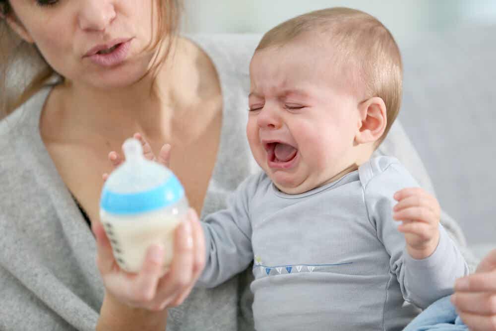 Bebé llorando con un biberón