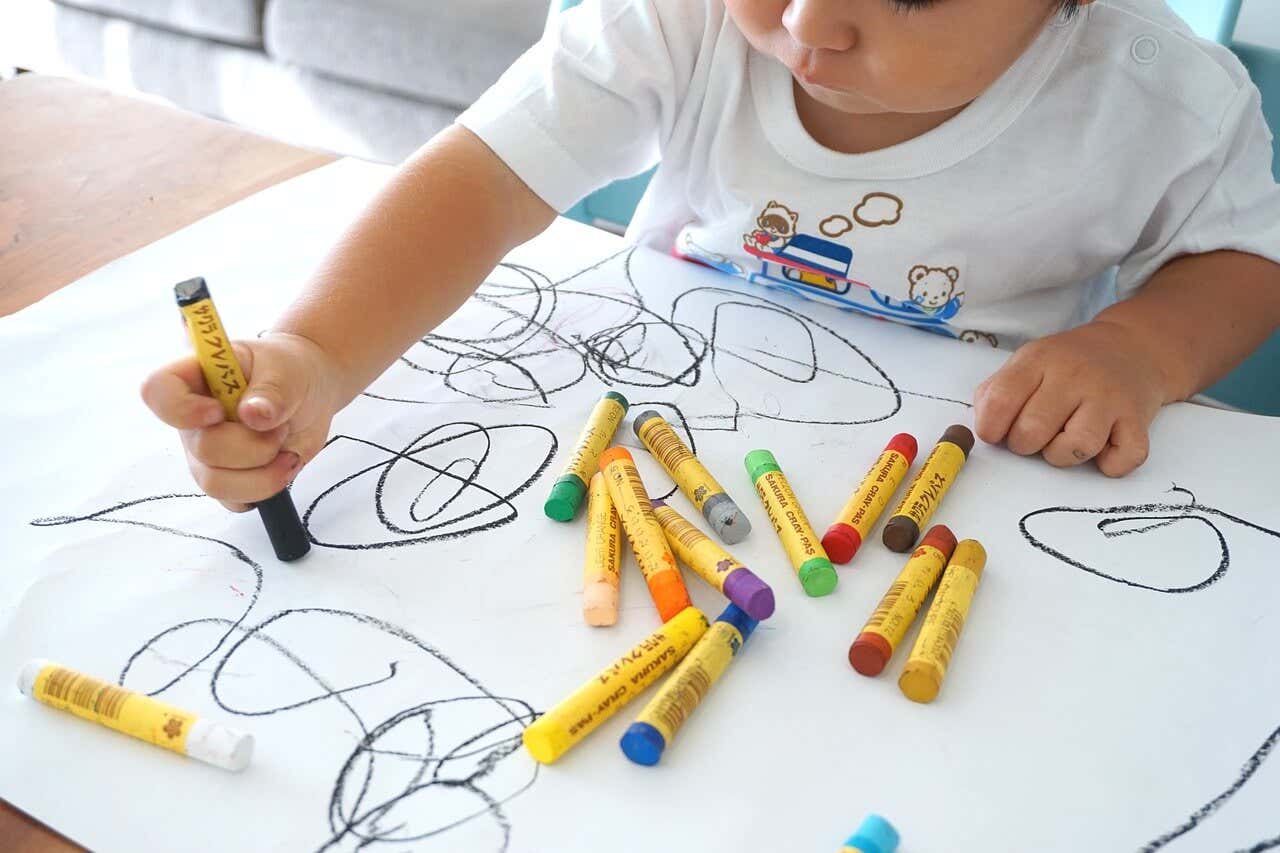 Niño dibujando con diferentes pinturas de colores.