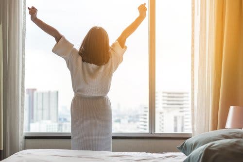 Mujer estirándose mirando por la ventana