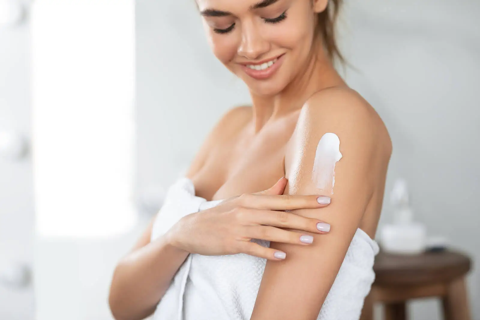 Mujer aplicándose crema hidratante.
