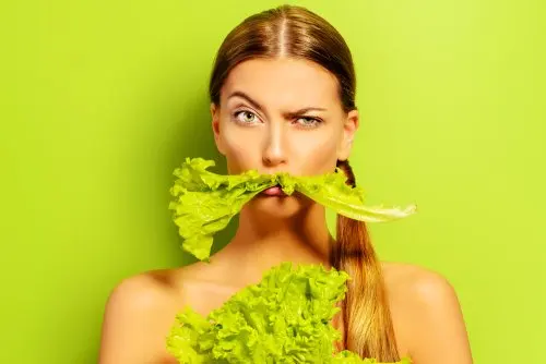 Mujer mordiendo un trozo de lechuga. hidratado