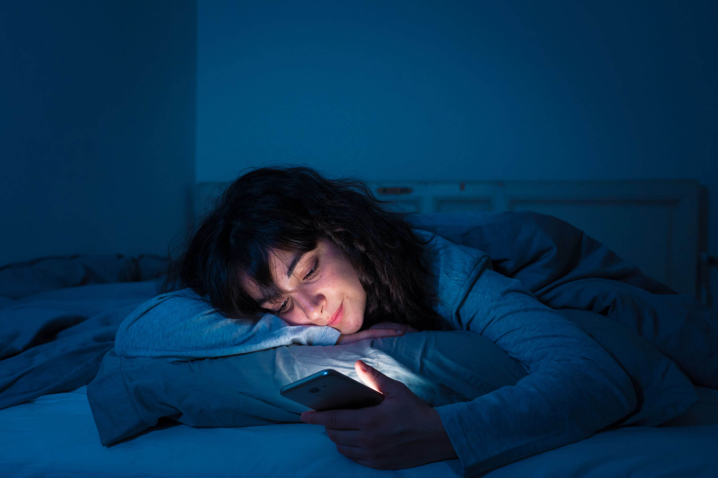 Mulher olhando o celular antes de dormir