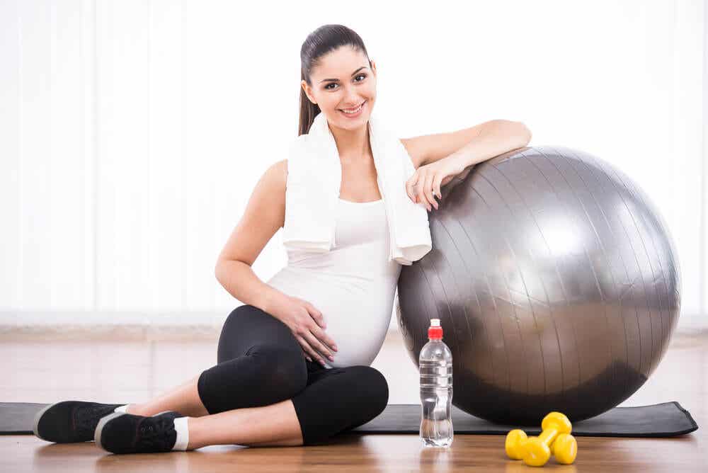 Mujer embarazada practicando deporte con una pelota de fitness.